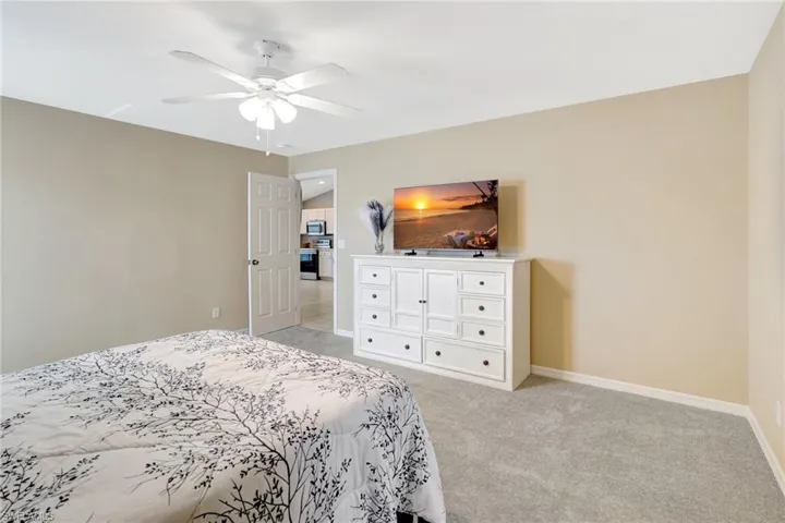 Bedroom featuring light carpet, baseboards, and ceiling fan
