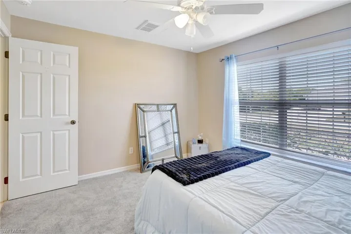 Carpeted bedroom with visible vents, baseboards, and ceiling fan