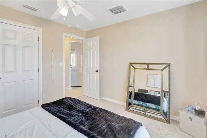 Bedroom featuring visible vents, ceiling fan, light colored carpet, and baseboards