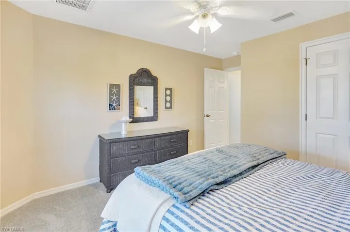 Bedroom with visible vents, baseboards, carpet flooring, and ceiling fan