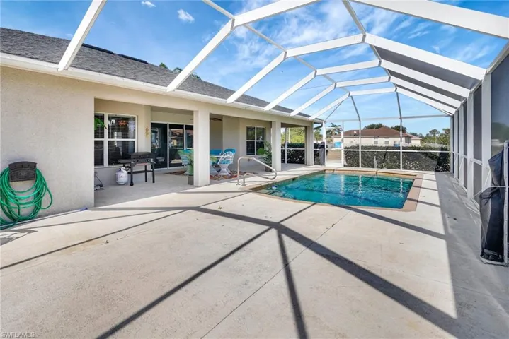 Outdoor pool with a patio area and glass enclosure