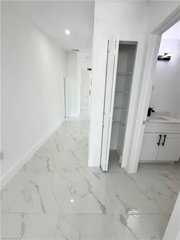 Hallway featuring light marble finish floors and recessed lighting