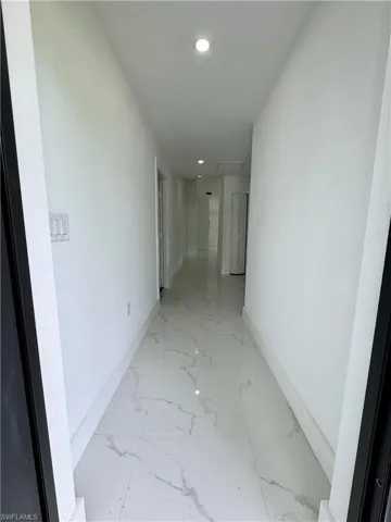 Hall with recessed lighting, light marble finish floors, and attic access