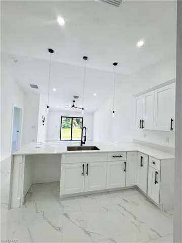 Kitchen with white cabinetry, pendant lighting, light marble finish floors, recessed lighting, and a ceiling fan