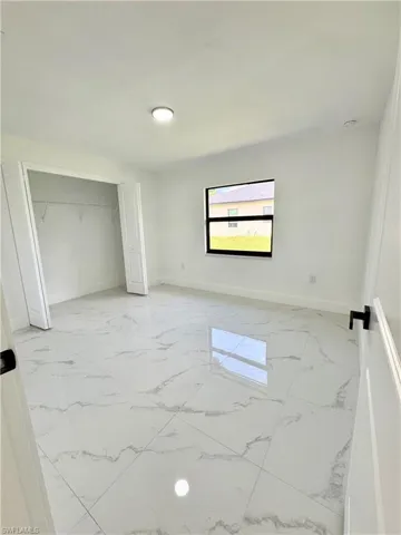 Unfurnished bedroom featuring light marble finish floors and a closet
