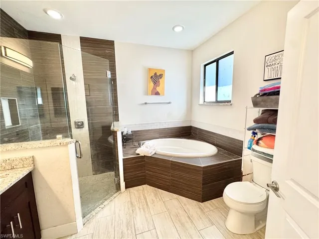 Bathroom featuring a garden tub, vanity, a shower stall, and recessed lighting