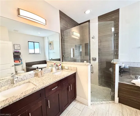 Bathroom featuring a shower stall, double vanity, and a bath