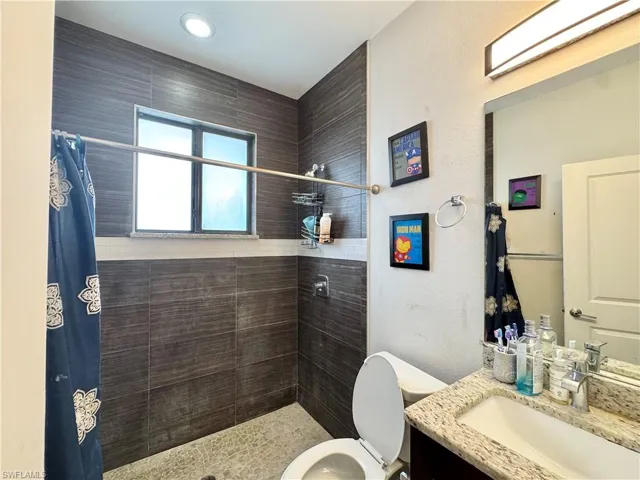 Full bathroom featuring vanity, a shower stall, and a textured wall