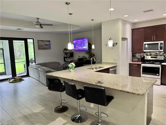 Kitchen featuring a peninsula, stainless steel appliances, open floor plan, tasteful backsplash, and a breakfast bar area