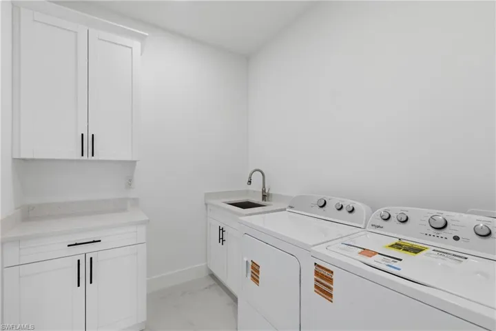 Laundry area with cabinet space, light marble finish flooring, and washer and clothes dryer
