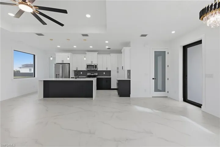 Kitchen with decorative light fixtures, a center island, white cabinetry, appliances with stainless steel finishes, and open floor plan