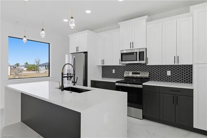 Kitchen with stainless steel appliances, white cabinets, pendant lighting, light stone countertops, and recessed lighting