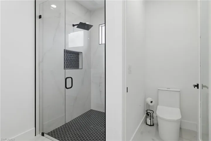 Full bathroom with toilet and a marble finish shower
