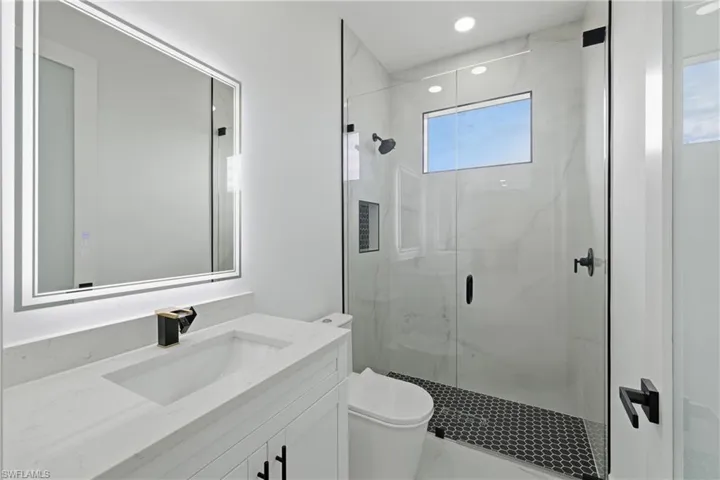 Full bath with a marble finish shower, vanity, and recessed lighting
