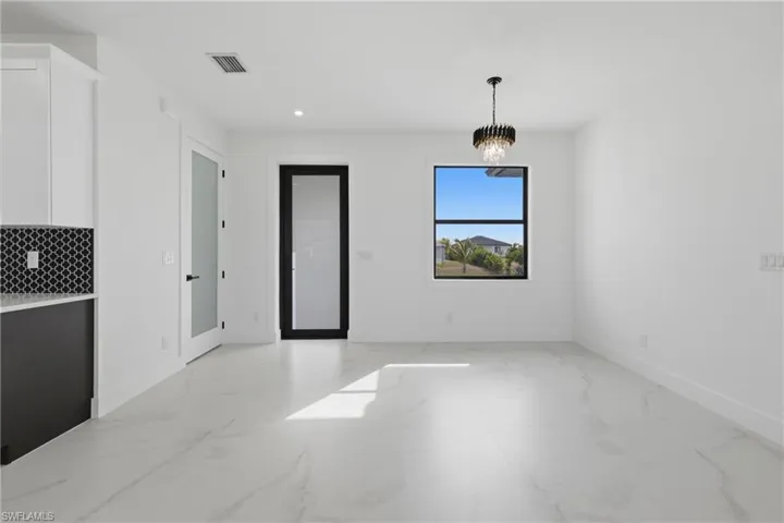 Unfurnished dining area featuring light marble finish flooring, recessed lighting, and a chandelier