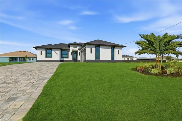 View of front of property with stucco siding, a front lawn, and driveway