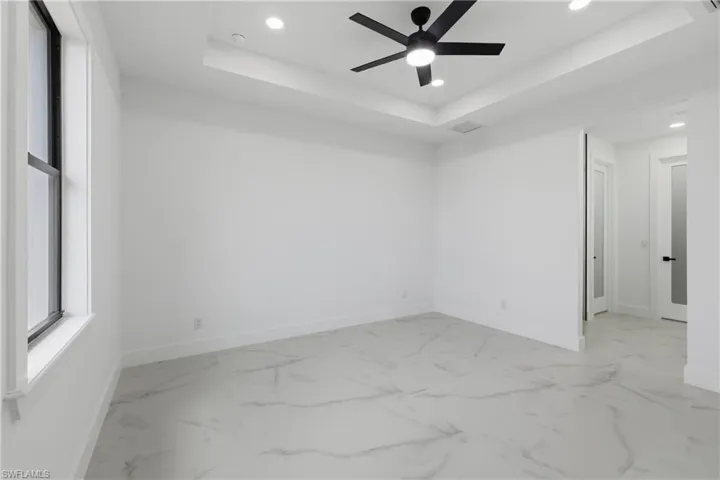 Unfurnished room featuring a tray ceiling, recessed lighting, and a ceiling fan