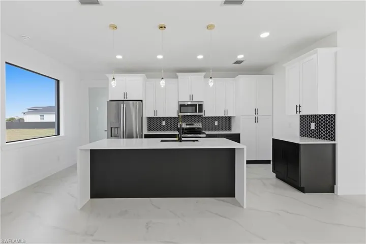 Kitchen featuring white cabinetry, decorative light fixtures, backsplash, stainless steel appliances, and recessed lighting