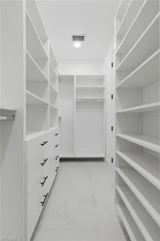 Spacious closet featuring light marble finish floors