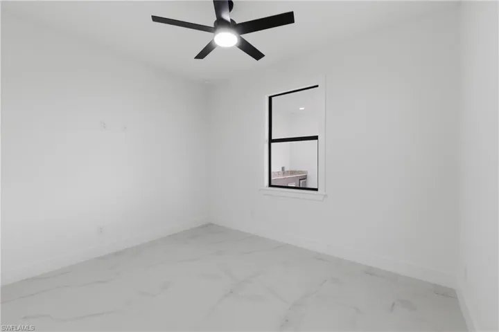 Empty room featuring light marble finish flooring and a ceiling fan