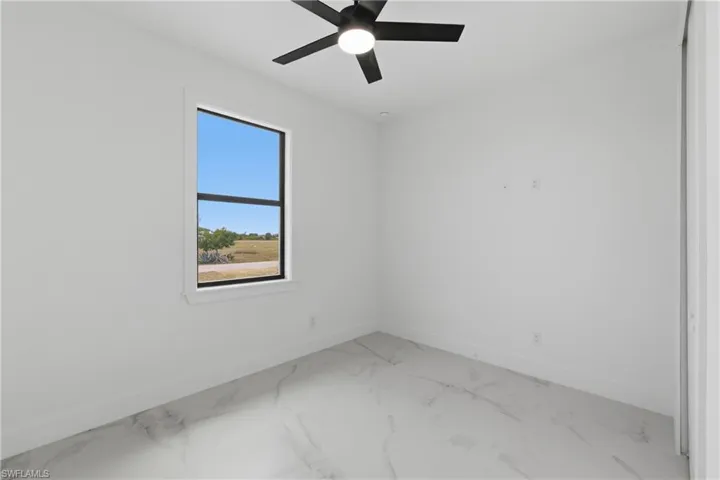 Empty room featuring light marble finish floors and a ceiling fan