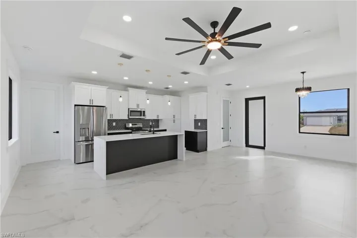 Kitchen with a tray ceiling, open floor plan, decorative light fixtures, and recessed lighting