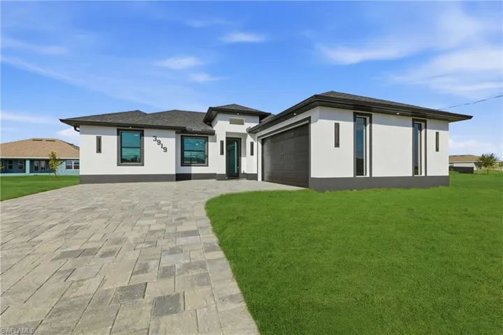 Prairie-style home with stucco siding, a front yard, driveway, and an attached garage