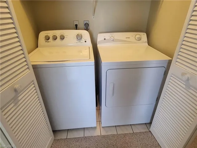 Laundry area featuring independent washer and dryer and light tile patterned flooring with tons of storage above