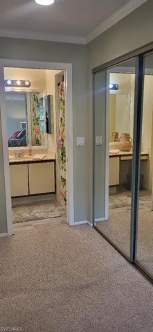Hallway with baseboards, carpet, and crown molding
