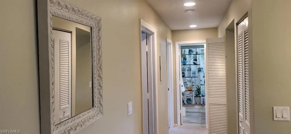 Hallway in primary suite with 2 closets  walkway to private primary bathroom featuring recessed lighting