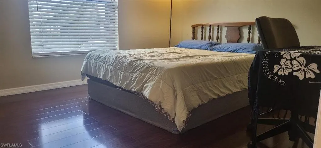 Bedroom featuring new dark wood-style wood flooring with bed and desk