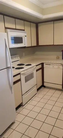 Kitchen featuring ornamental molding, white appliances, light countertops, and light tile patterned flooring