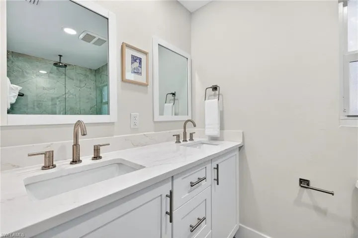 Primary Bathroom with a marble finish shower and double vanity