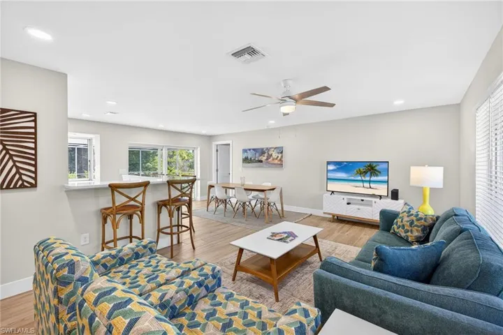 Living area featuring light wood-style flooring, plenty of natural light, and a ceiling fan