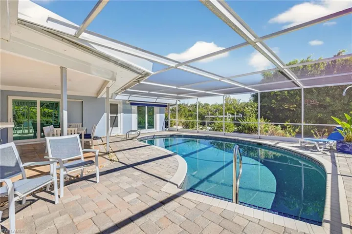 Swimming pool with glass enclosure, a sunroom, and a patio