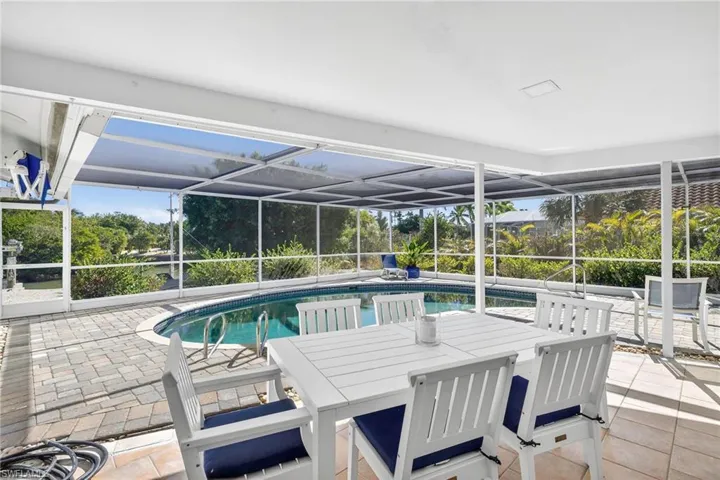 Outdoor pool with a sunroom, a lanai, a patio, and outdoor dining space