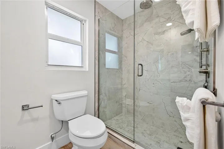 Primary Bathroom featuring toilet and a marble finish shower