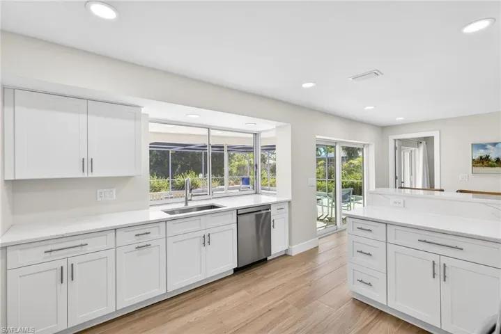 Kitchen featuring white cabinetry, light stone countertops, stainless steel dishwasher, light wood finished floors, and recessed lighting
