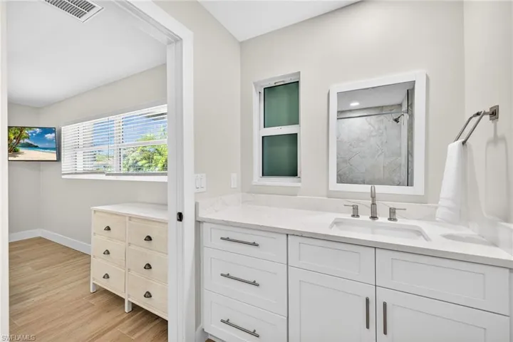 Full bath featuring vanity, a marble finish shower, and light wood-style flooring