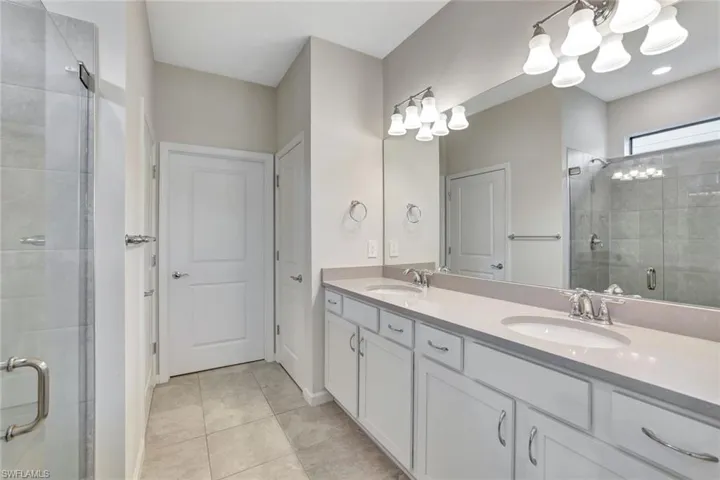 Bathroom featuring vanity, tile patterned floors, and a shower with shower door