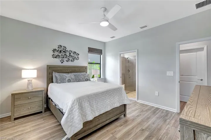 Bedroom with light wood-type flooring, ceiling fan, and connected bathroom