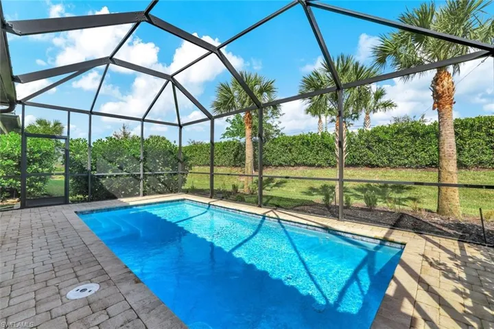 View of swimming pool featuring glass enclosure and a patio area