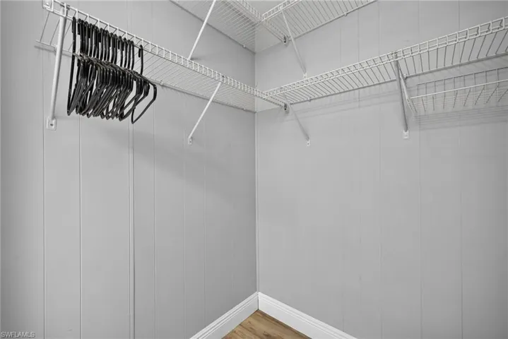 Storage space featuring multi-level white wire shelving and wood-finish flooring