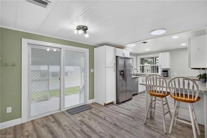 Kitchen featuring white cabinetry, stainless steel appliances, wood-finish flooring, sliding glass door, and recessed lighting