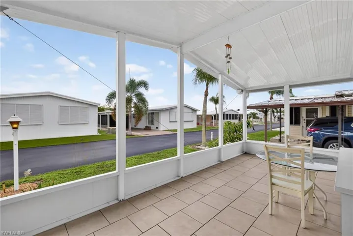 Screened lanai featuring tile flooring, a solid panel roof, and white structural framing
