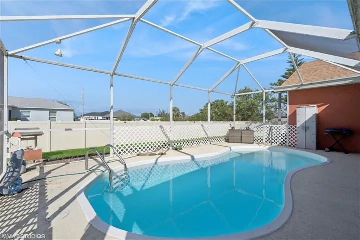 View of pool with enclosure, a patio, a fenced in pool, and fence