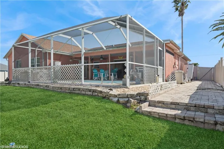 Back of property with enclosure, a patio, a gate, and a yard