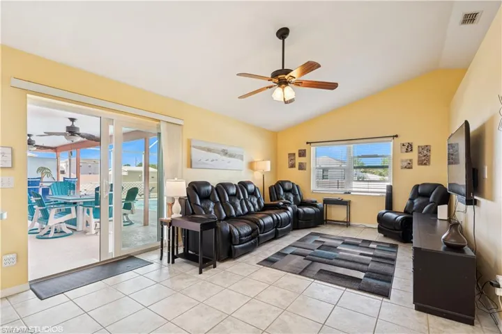 Tiled living area featuring lofted ceiling, a ceiling fan, and visible vents