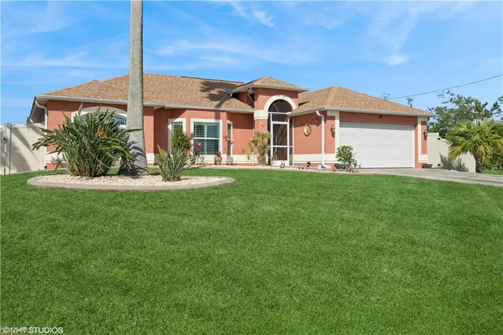 Ranch-style home featuring stucco siding, driveway, a front lawn, fence, and an attached garage