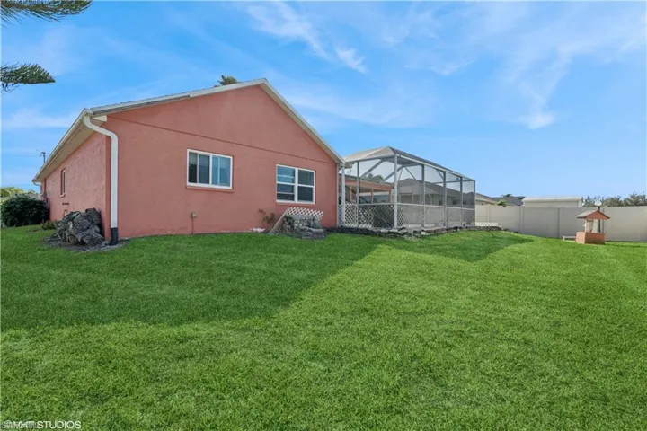 Rear view of property with enclosure, a yard, fence, and stucco siding